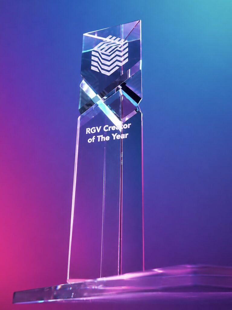 A glass RGV Creator of the Year trophy illuminated with blue and pink lighting.