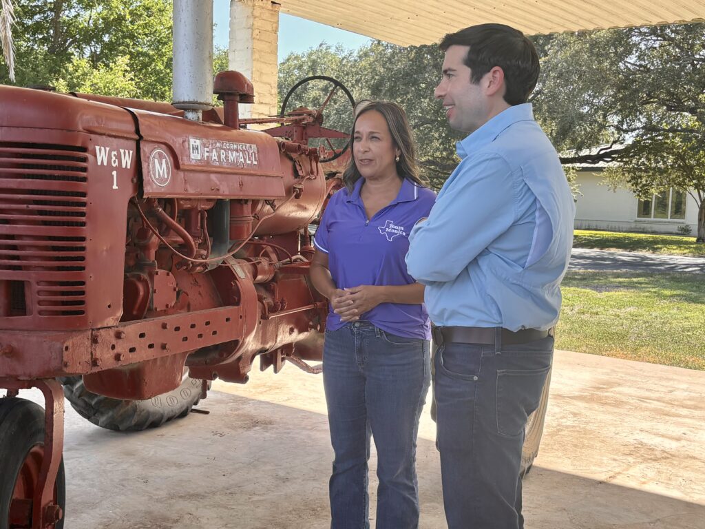 Rep. Monica De La Cruz and Acting Labor Secretary Keith Sonderling stand beside a vintage Farmall tractor during a visit to Rio Farms.