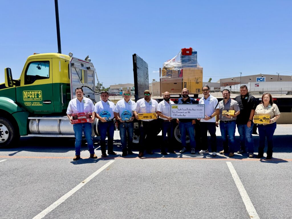 McCoy’s Building Supply representatives and academy partners pose with a $10,000 donation check and construction tools.