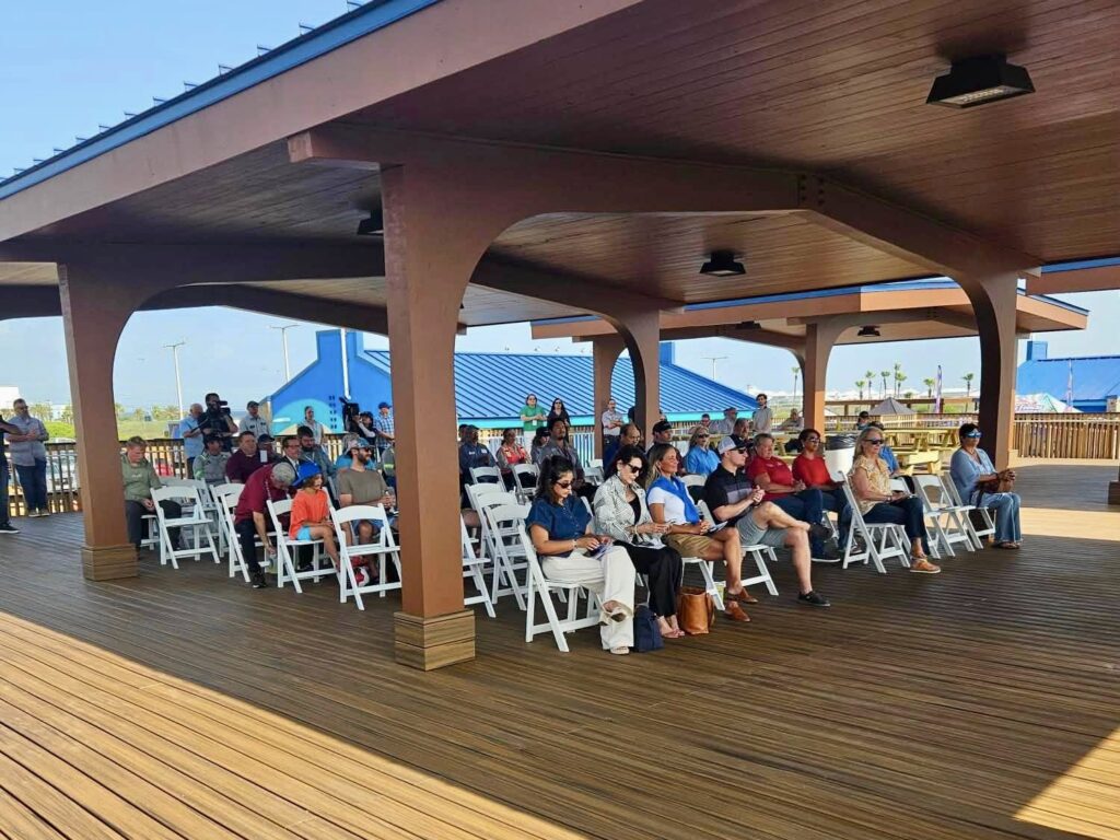 People seated beneath a newly constructed pavilion during the Andy Bowie Park ribbon-cutting ceremony on South Padre Island.