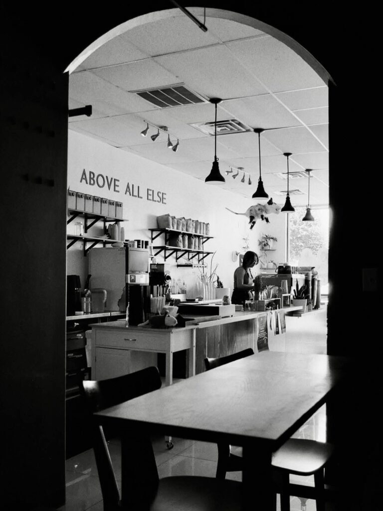 The interior of a Sovereign Coffee shop with a barista working behind the counter.