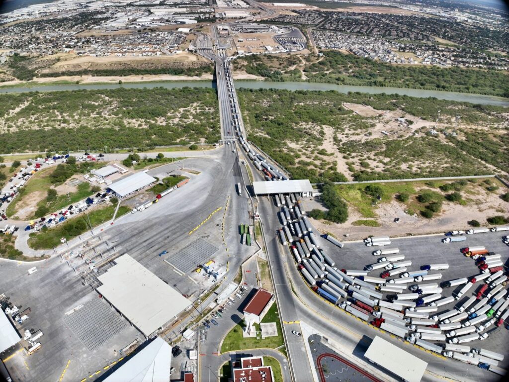 Una vista aérea de camiones comerciales alineados en un puente internacional de Nuevo Laredo que cruza el Río Grande hacia Texas.