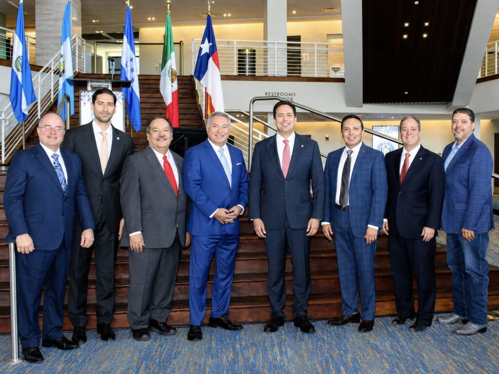 McAllen and Saltillo officials pose together on a staircase surrounded by the flags of the United States, Mexico, Texas and Central American countries.