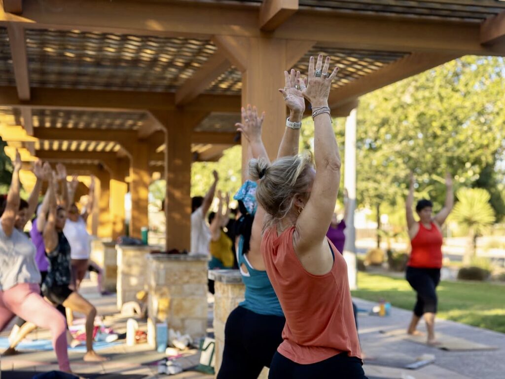 Participants raise their arms during an outdoor yoga class in Brownsville’s Mitte Cultural District.
