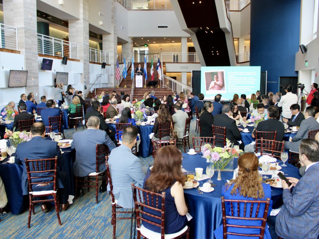 Attendees sit at banquet tables facing a speaker and presentation screen during a McAllen event focused on ties with Saltillo, Mexico.