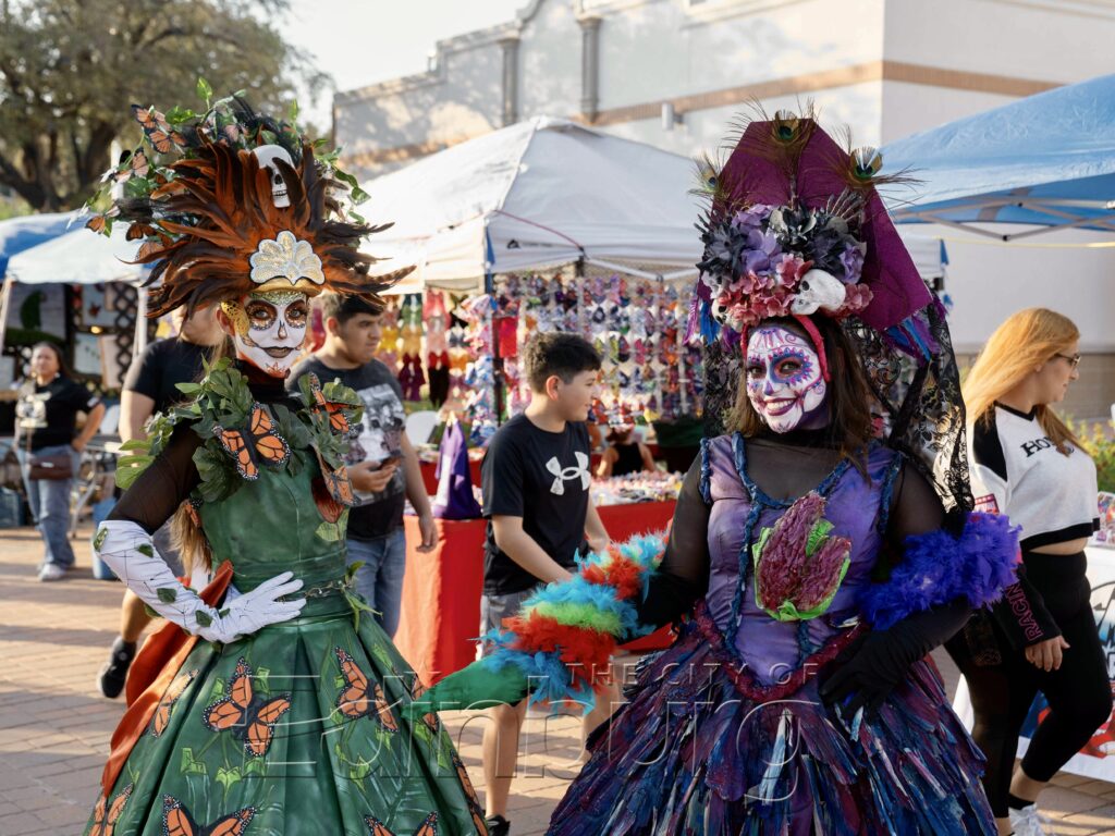 Two performers wearing colorful Día de los Muertos costumes and face paint at Edinburg’s Los Muertos Bailan celebration.