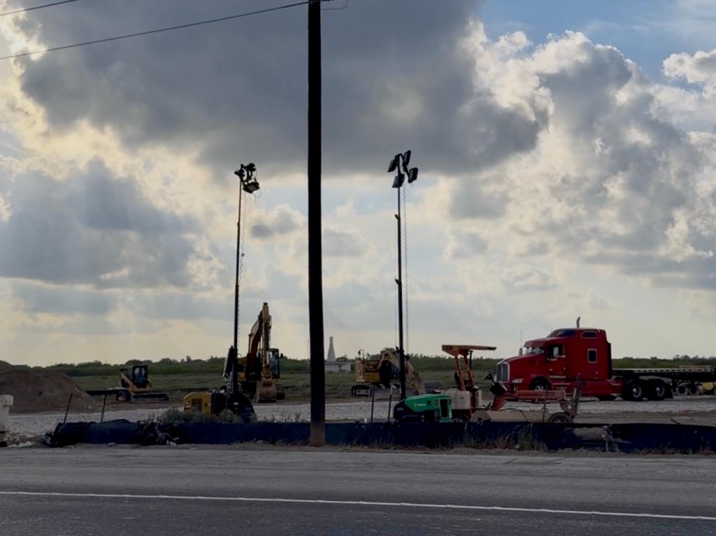 Excavators, construction equipment and a red semi-truck sit at an active construction site near the Brownsville landfill.