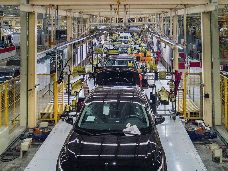 Vehicles in various stages of assembly move along a production line inside a Nissan manufacturing plant.