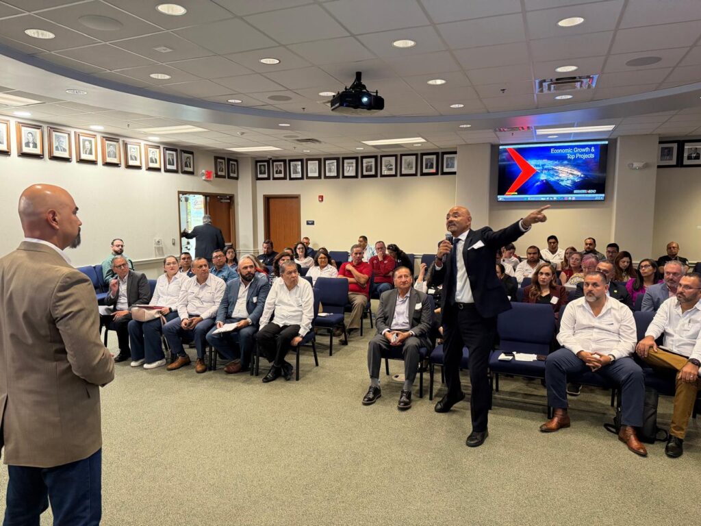 Nester Leao Contreras gesticula con ambas manos mientras habla durante un debate sobre la fuerza laboral con Gilberto Salinas, director ejecutivo de Greater Brownsville EDC, y otros asistentes.