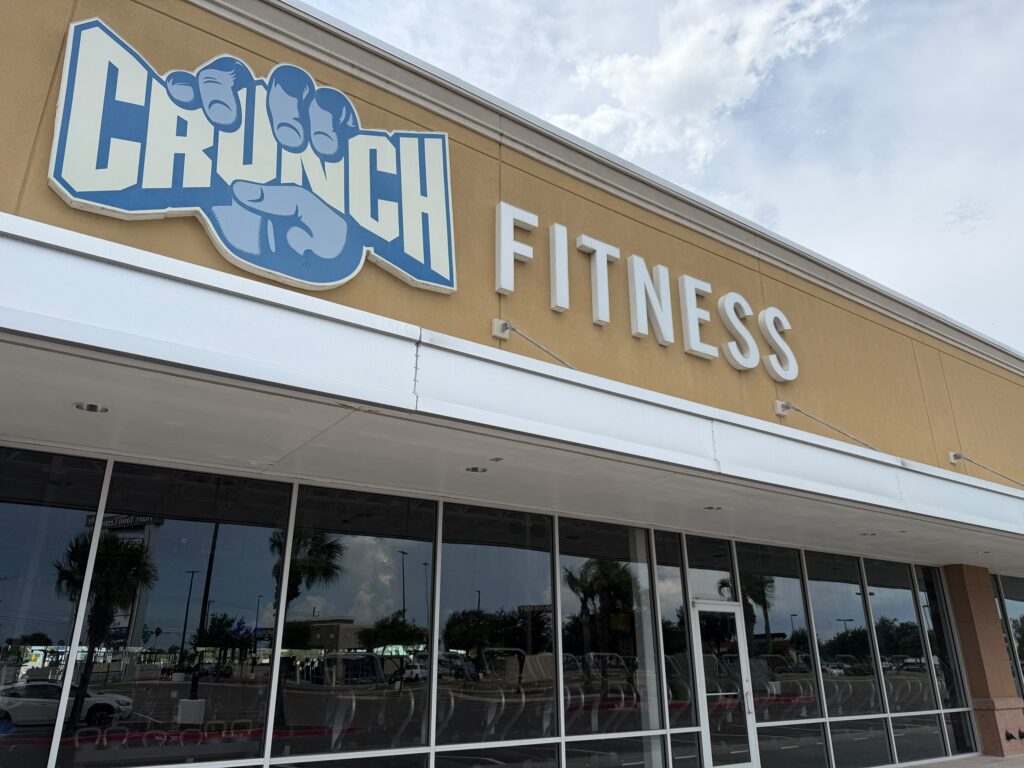 The Crunch Fitness storefront in Pharr with the gym’s blue-and-white sign above large front windows.